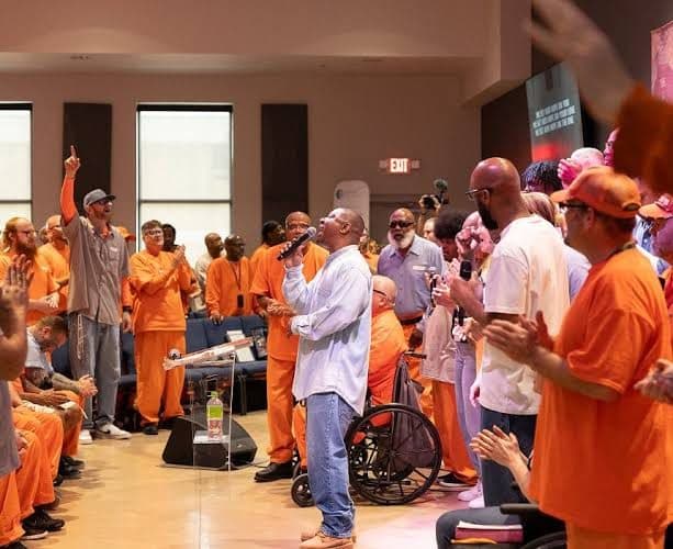 A worship service inside a prison, men standing and singing